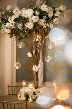 a vase filled with white flowers sitting on top of a table next to a candle