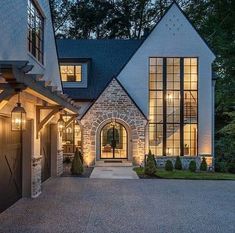 a large house with lots of windows and lights on it's front door is lit up at night