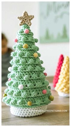 a crocheted christmas tree sitting on top of a table next to a small child