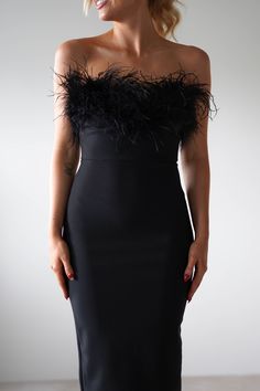 a woman wearing a black dress with feathers on it