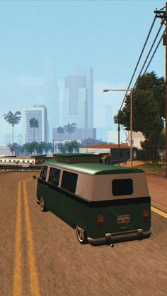 a green and white van driving down a road next to a tall cityscape