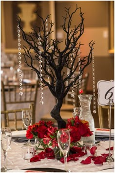 the centerpieces are decorated with red flowers and branches, along with crystal beads