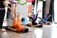 a group of people doing yoga on mats in a room with balloons and streamers