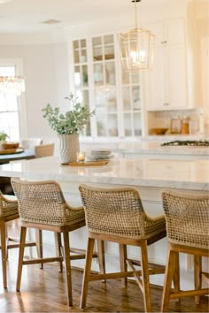 a kitchen island with four chairs and a potted plant on it in the center