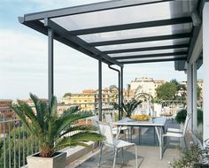 an outdoor dining area with white chairs and table on the balcony overlooking cityscape