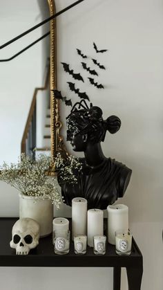 a table topped with candles next to a mirror and a skull statue on top of it