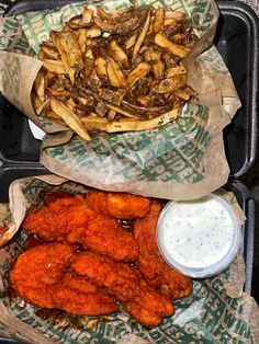 two trays filled with french fries and other food on top of paper wrappers