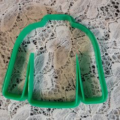 two green cookie cutters sitting on top of a lace tablecloth