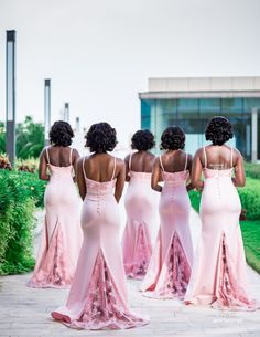 four women in pink dresses are walking down the street together and one woman is wearing an open back dress