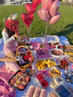 a woman sitting at a table with lots of food and balloons in the shape of hearts