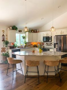 a large kitchen with an island in the middle and three stools at the counter