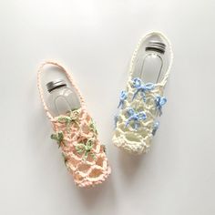 two crocheted shoes with bows on them sitting next to an empty glass bottle