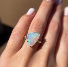 a woman's hand holding an opal ring