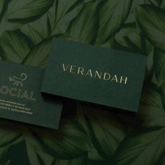 two business cards sitting on top of each other in front of green leafy wallpaper