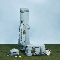 a golf bag sitting on top of a green field next to two bags and balls