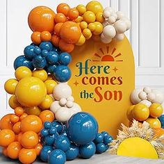 there is a balloon arch that says here comes the son