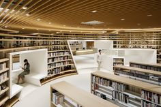 two people sitting in the middle of a library filled with books