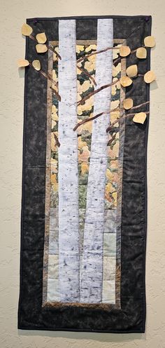 a quilted wall hanging with trees and leaves