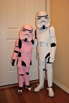 two people dressed up as stormtroopers standing next to each other in front of a door