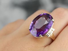 This is a stunning stone, with a rich color and a sophisticated cut. This natural, well-cut amethyst at the center glimmers with its medium-deep eggplant purple color that flashes with pops of violet and raspberry. We've set this pretty gem into a vintage mounting of yellow gold. Easy to wear, this sits comfortably on the finger and is a nice, bold size that is sure to make a statement! Metal: 14K Yellow Gold Gem: Amethyst 19.50 Carats Gem Measurements: 15.9 x 20.8 mm, Oval Ring Size: 5.50 Marks Amethyst Stone Ring, Oval Stone Ring, Amethyst Cocktail Ring, Gold Drop Necklace, Beautiful Rings Vintage, Big Stone Ring, Right Hand Ring, Pearl Jewelry Design, Right Hand Rings