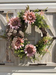 a leopard print wreath with pink flowers and greenery hangs on a white wooden door