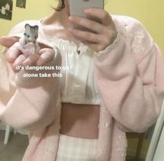 a woman taking a selfie with her cell phone in front of her face and wearing a pink cardigan