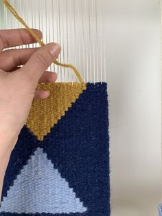 a person is weaving on a blue and yellow rug