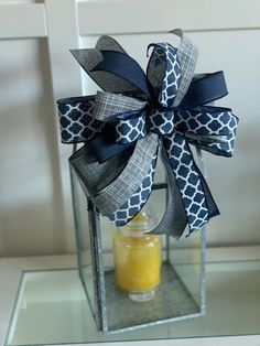 a glass vase with a blue and white bow on it's side next to a jar filled with orange juice