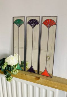 three mirrors sitting on top of a radiator next to a vase with flowers