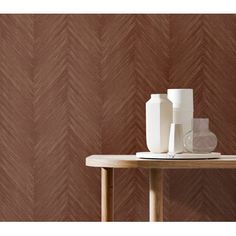 two vases sitting on top of a wooden table next to a brown wallpaper