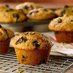 blueberry muffins cooling on a rack with other muffins in the background