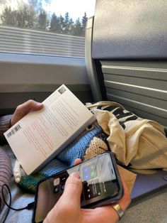 someone is reading a book and using their cell phone to read the text on the train