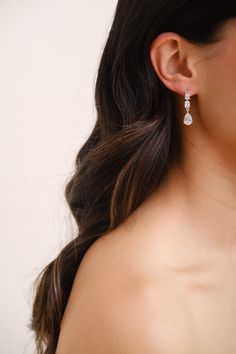 a close up of a woman's face wearing earrings with diamond drops on them