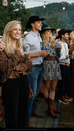 a group of people standing next to each other on a wooden deck with mountains in the background