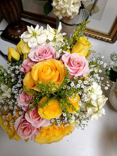 a bouquet of flowers sitting on top of a white table next to a mirror and vase