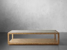 a wooden table with a glass top in front of a gray wall and concrete floor