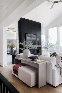 a living room filled with furniture and a fire place next to a large window on top of a hard wood floor