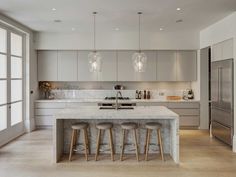 a kitchen with marble counter tops and stools next to an island in the middle