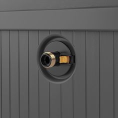 a black and gold light switch on the side of a gray wall with wood paneling