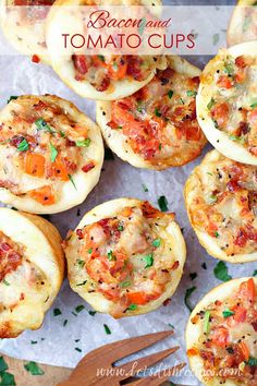 bacon and tomato mini pizzas on a sheet of parchment paper with utensils