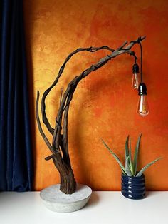 a tree branch lamp sitting on top of a table next to a potted plant