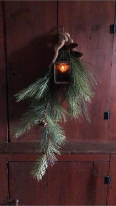 a candle is hanging from a pine branch on a door handle with twine needles