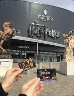 someone holding up some photos in front of the entrance to harry potter's studio