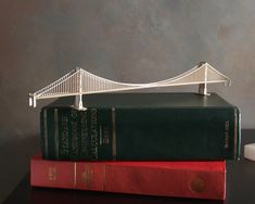 two books are stacked on top of each other with a miniature bridge in the background