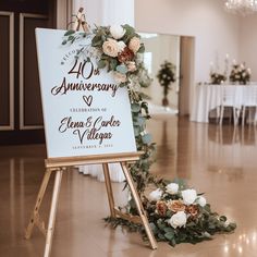 a sign that is on top of a wooden easel with flowers and greenery