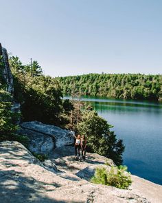 two people standing on the edge of a cliff overlooking a lake