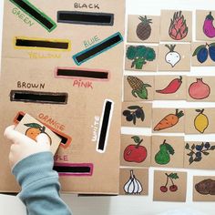 a young boy is playing with some fruit and vegetables magnets on a piece of cardboard