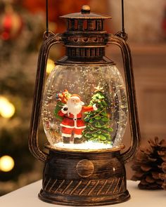 a snow globe with santa clause in it on a table next to a pine cone