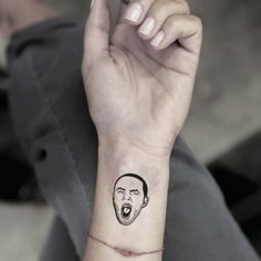 a person with a face tattoo on their wrist