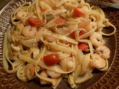 pasta with shrimp and tomato sauce in a brown bowl next to a silver fork on a table